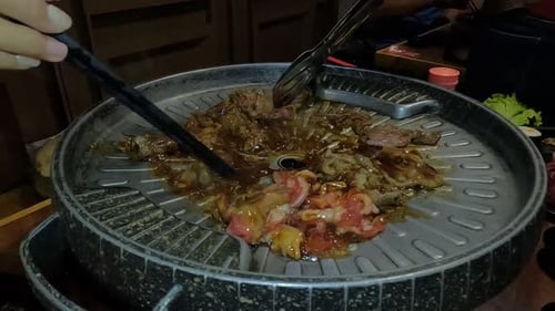 People prepare meat on Korean barbecue in restaurant, close up