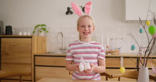 Porträt eines fröhlichen Mädchens mit Hasenohren und bunten Eiern in ihren Händen während der Osterzeit