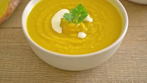 Pumpkin Soup in White Bowl with Cream and Parsley