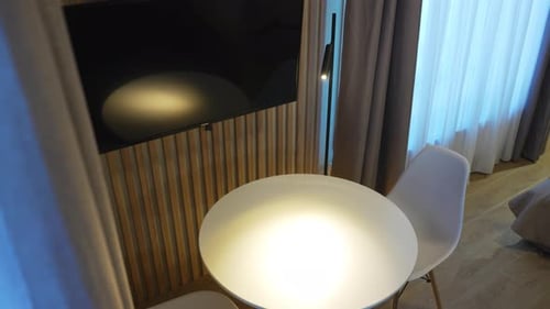 White Round Table with Chairs Under Tv Set in Hotel Room