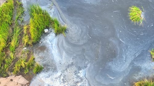 Aerial of Swirling Pollution on Body of Water