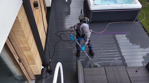 Man Cleaning Wooden Decking with a Pressure Washer