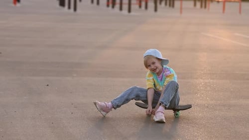 Fashionable Little Girl Sitting on a Skateboard in the City