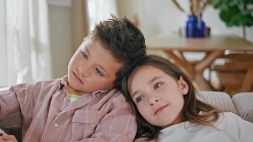 Children Relaxing Together on Sofa Indoors
