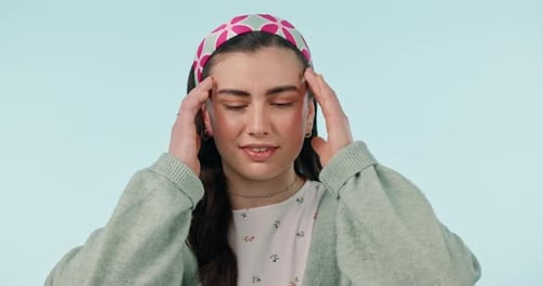 Headache, anxiety and face of woman in studio with stress, fear or worry on blue background space