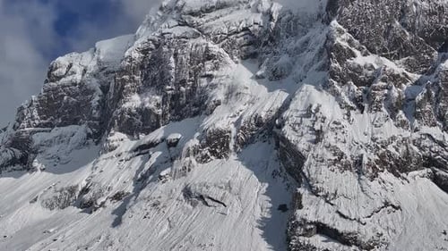 vista aérea de los escarpados acantilados cubiertos de nieve de Fronalpstock bajo un cielo parcialmente nublado en Glarus N