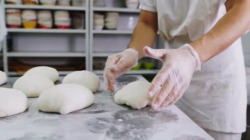 Baker Works with Dough at Metal Table in Workshop Closeup