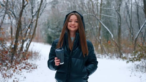 Happy relaxed woman with long brunette hair walks by the park in winter.