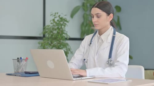 Young Female Doctor Working on Laptop in Clinic