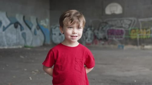 Un jeune garçon s'amuse et fait des expressions devant la caméra dans un t-shirt rouge, mains b