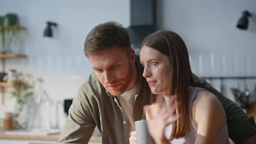 Young Couple Using Laptop in Sunny Kitchen