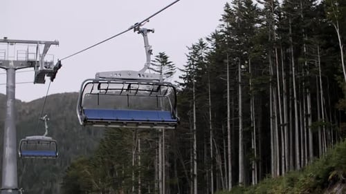 Ski Lift Transports People Up Mountain on Cloudy Day