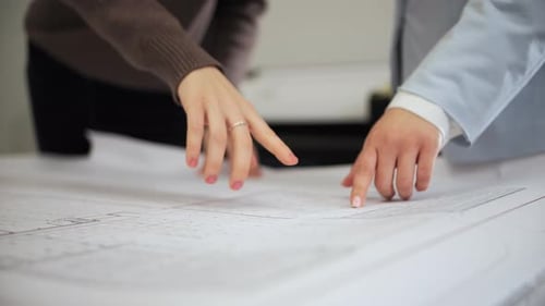 Female Professionals Reviewing Blueprint Together in Office