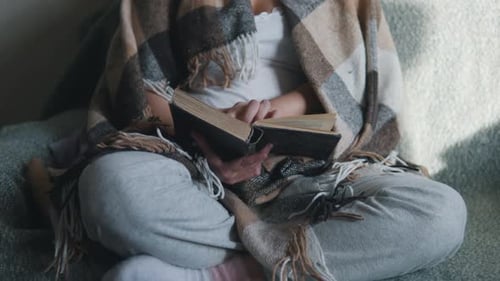 Female Hands Turning Pages Woman Under Cozy Blanket Reading Book Close Up