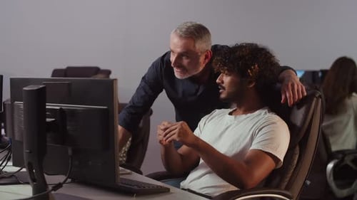 A Young Man Working in an IT Company is Typing Something on the Keyboard While Sitting in the Office