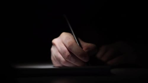Man Writing Ideas While Working on Laptop
