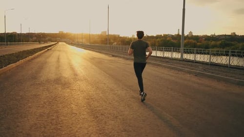 Male Jogger is Training Outdoor in Summer Morning Rear View of Athletic Man Running on Road