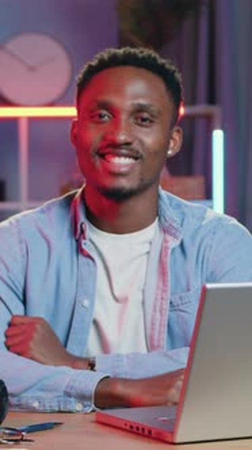 Goodlooking Highskilled Cheerful Young Man Sitting at the Desk in Cozy Home Office with Colourful