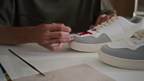 Artist Painting Custom Designs on White Sneakers