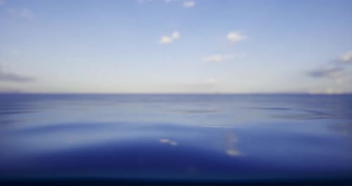 Calm Ocean Waters Under a Clear Blue Sky with Scattered Clouds at Sunset
