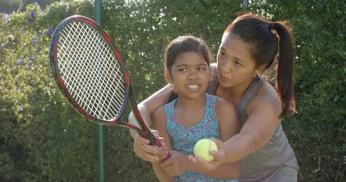 Child Learning Tennis With Adult Instruction Outdoors