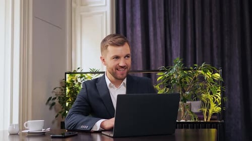 Smiling Business Man Working on Laptop Computer in Restaurant