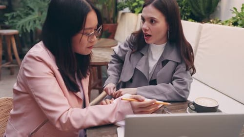 Two Female Entrepreneurs Planning a Startup at a Cafe