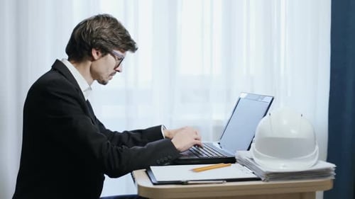 Ein Bauingenieur arbeitet an einem Laptop. Die Berechnung und Planung von Zeichnungen.