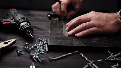 Carpenter is Marking a Board for Drilling