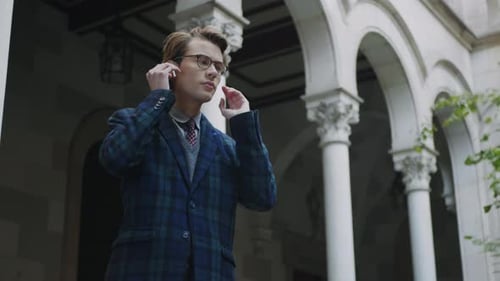 Cheerful College Student Using Wireless Earphones Outdoors. Portrait of Smiling Businessman Listenin