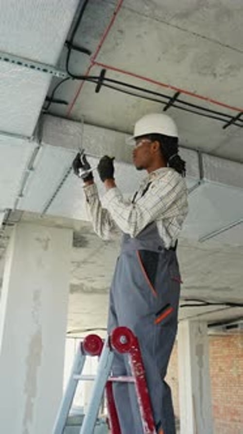 Construction Worker Wiring Ceiling in Commercial Building