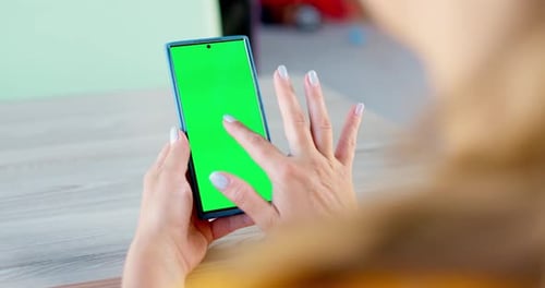 Back View of Young Woman Holding Smartphone with Green Screen and Looking on It