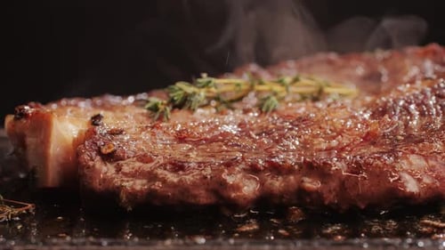 Fresh Marbled Beef with Pepper Salt and Rosemary Closeup Macro Cooking Juicy Steak on Grill with Oil