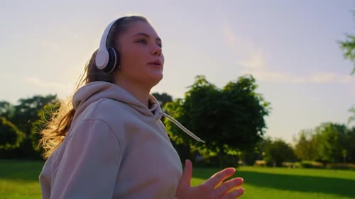 Young woman jogging in the park during sunset