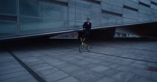 Businessman Stands On Bike Saddle And Stem