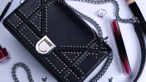 Rotating Background with Trendy Black Handbag and Decorative Cosmetics Nail Polish Makeup Brushes