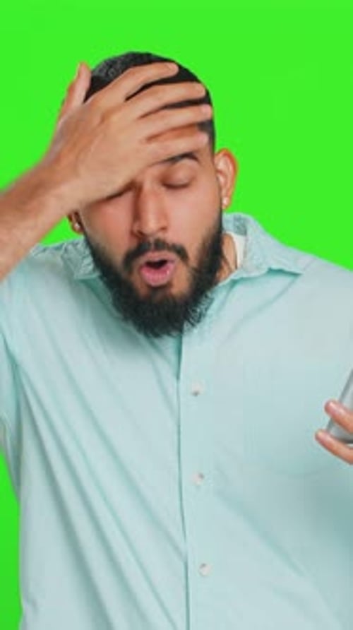 Bearded Man Using Phone on Green Screen Expressing Disgust