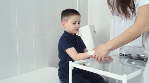 Young Boy Getting His Hand Bandaged by Doctor