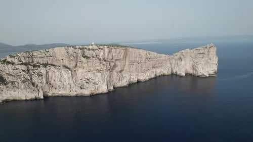 Aerial top view of a sea cliff in a blue ocean at sunset. Sea waves on beautiful landscape aerial vi