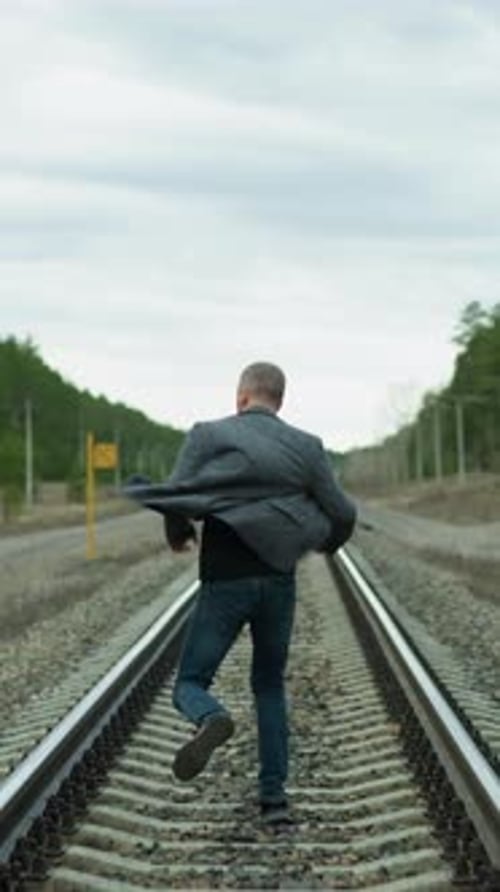 Man Running on Railroad Track Through Rural Landscape