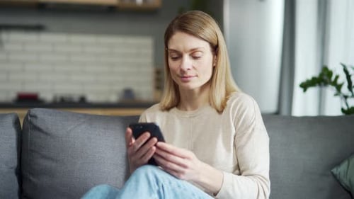 Woman Using Smartphone Sitting on Couch At Home