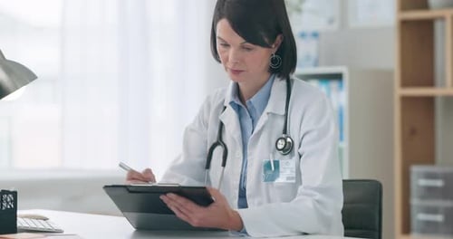 Female Doctor Writing on Clipboard in Office