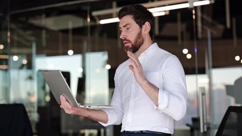 Businessman Having Video Call on Laptop in Modern Office