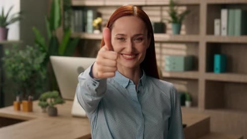 Smiling Woman Giving Thumbs Up in Office