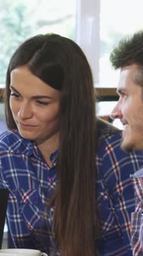 Friends Gathered Around a Laptop at a Cozy Coffee Shop Enjoying Breakfast