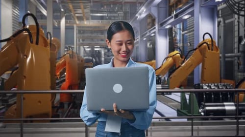 Woman Holding Laptop in Automated Factory Setting