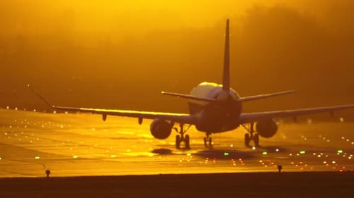 Sunset takeoff of a passenger plane from a busy airport runway