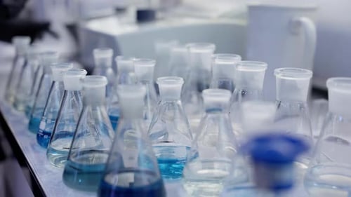 Scientific Laboratory A Row of Flasks Stand on the Table Handheld Camera Closeup Slow Motion A