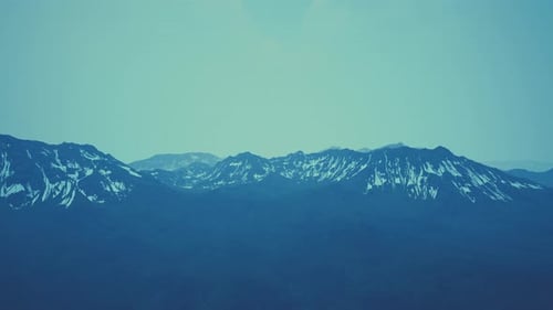 Awesome Top View Through Clouds to High Snowy Mountains