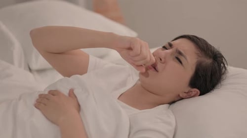 Jeune Indienne malade toussant alors qu'elle est couchée dans son lit